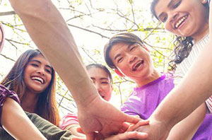 Image of teens with their hands touching